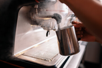 Barista steaming milk on a coffee machine at cafe