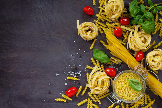 Ingredients for the preparation of Italian pasta - spaghetti, fusilli, fettuccine, basil, cherry tomato and pepper. Top view with space for text.