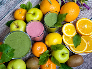 A lot of ripe juicy fruit and three glasses of smoothies on a wooden table