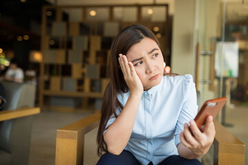 Woman using smartphone in cafe and she feel worried