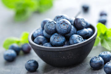 Fresh Blueberries in a bowl on dark background, top view. Juicy wild forest berries, bilberries. Healthy eating or nutrition.