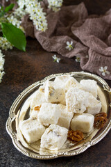 Rahat Lokum with walnuts on the kitchen table. Turkish and Arabic sweets. Ramadan food. Copy space.