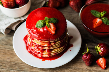Close-up american pancakes and strawberry sauce on a wooden background. Shallow depth of field.