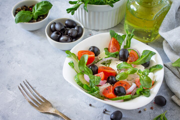 Greek salad with arugula, tomatoes, feta cheese, onions, cucumber and olives, seasoned with oil. Vitamin snack on the festive table.