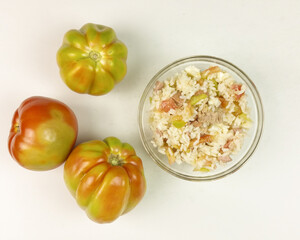 Tomatoes and simple rice salad in a transparent bowl on white background - top view