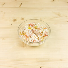 Simple rice salad in a transparent bowl on wooden background - top view