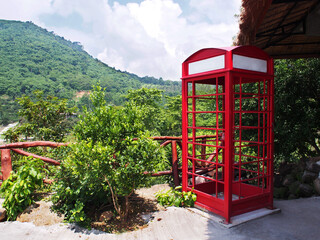 Red telephone booth against green tree background