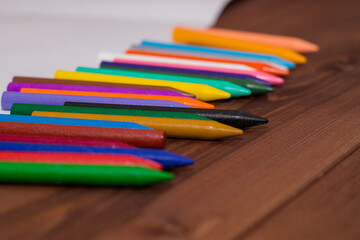 Fototapeta premium Colorful crayons with a white blank sheet of paper on a wooden background