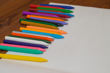 Fototapeta premium Colorful crayons with a white blank sheet of paper on a wooden background