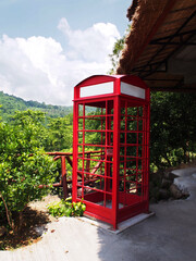 Red telephone booth against green tree background