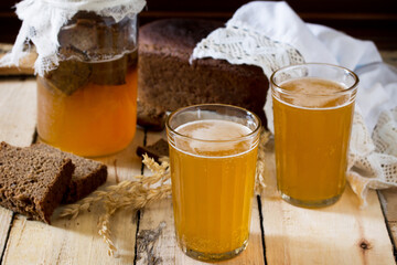 Traditional Russian cold rye drink Kvas in a glass and a jug on a wooden table. Kvass from bread, rye malt, sugar and water.