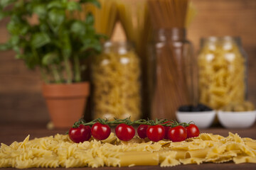 Many types of Italian pasta with olives and basil on background