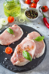 Raw fillet steak with cherry tomatoes, basil, onion and spices cooking on a stone kitchen table.