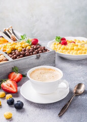 Healthy breakfast with coffee, variety of cold quick cereals and berries in old gray wooden box, selective focus.