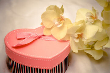 gift box in form of heart on the background of the yellow orchid
