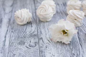 Fototapeta na wymiar White zephyr and white flower on grey wooden background