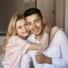 Young romantic couple at home. Caucasian blonde woman and brunette man. Lovers hugging in living room.