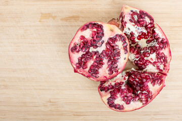 Broken red ripe juicy pomegranates on wooden table.