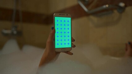 4k uhd Young sexy Girl use mobile phone in foam bath vertical in hotel room number. Shower white device with green screen and blue cross for tracking close-up.