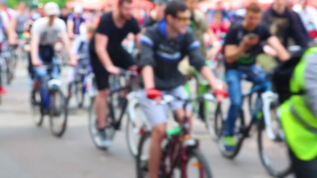 Blurry shot of many people of different age riding bikes in city street during public charity marathon. Real time full hd video footage.