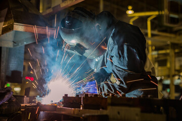 Industrial worker is welding metal in factory
