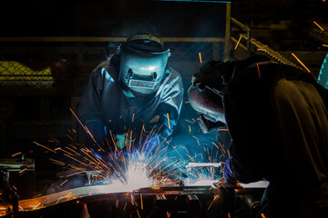 Team workers are welding part in factory
