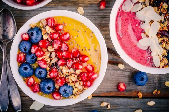 Healthy summer breakfast mango and raspberry smoothie bowl with granola, blueberries, pomegranate and chia seeds