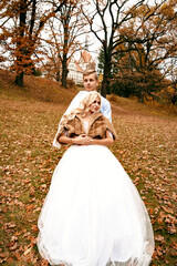 Beautiful young wedding couple stand happy together in a park in a white dress with a veil and a fur coat, hug, man and woman together, young family