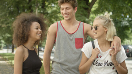 Obraz premium Three friends talking to each other as they walking together on a park trail. 