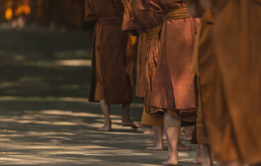Fototapeta na wymiar Buddhist Monks Line up in Row Waiting for Buddhism People to Give Alms Bowl in Thai Temple.
