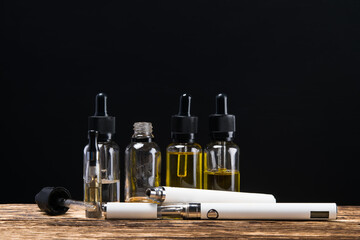 Fototapeta na wymiar electronic cigarette with flavors a couple in the bottle on the Board with a black background
