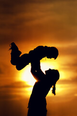 Silhouettes of mother and son playing outdoors