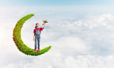 Concept of careless happy childhood with girl on green moon