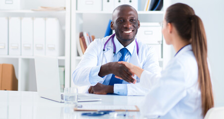 Fototapeta premium Two happy smiling young medical people handshaking at office