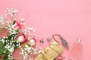 beautiful roses next to pearls and perfume on wooden background.