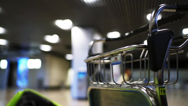 4k ultra hd. Emty airport luggage cart standing in departure or arrival zone with blurred people at the background waiting for their gate opening. Metal and plastic tripod shot. Time waste concept