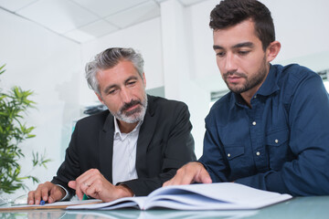 Two businessmen looking at book
