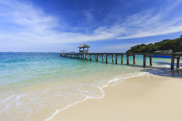 Wood bridge pier on summer tropical sea in blue sky.