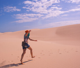 Girl with arms raised jumping in the sand in the desert. People in the desert.