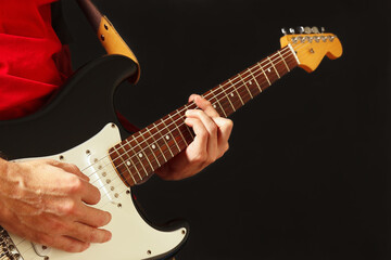 Posing hands of musician playing the guitar on the black background