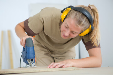 Woman using electric jigsaw