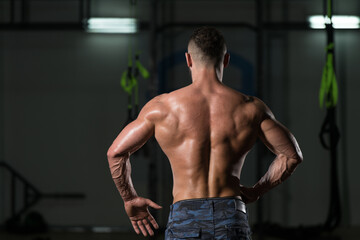 Fototapeta na wymiar Muscular Body Builder Showing His Back Lat Spread
