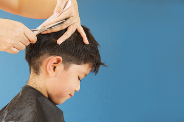 A boy is cut his hair by hair dresser