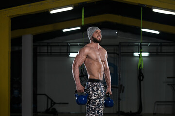 Fototapeta na wymiar Fitness Man Using Kettlebells Inside Gym
