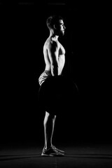 Fitness training. Man doing exercises or training with barbell in dark gym.