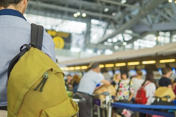 Soft focused picture of traveler over blurred long passenger queue waiting for check-in at airport check-in counters