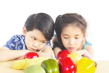 Fototapeta na wymiar Asian boy and girl showing dislike expression with fresh colorful vegetables isolated over white background