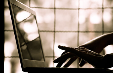 silhouette black and white of anonymous hacker typing on keyboard of laptop for remotely hacking...