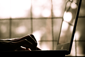 silhouette black and white of anonymous hacker typing on keyboard of laptop for remotely hacking...