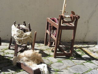Old spinning wheel, raw wool yarn and wool to card